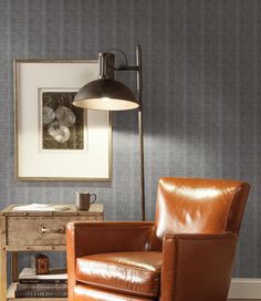 a brown leather chair sitting in front of a lamp on top of a wooden table