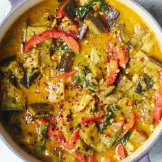 a pan filled with vegetables and sauce on top of a white countertop next to a spoon