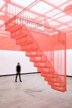 a person standing in front of a pink structure with a stair case on the floor