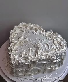 a large white cake sitting on top of a white platter covered in frosting