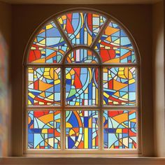 a large stained glass window sitting in the corner of a room next to a wall