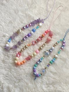 four necklaces with beads and charms on a white furnishing area, one is laying down