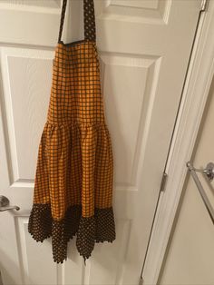 an orange and black dress hanging on a door handle in front of a white door