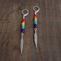 two pairs of earrings with rainbow colored beads and silver hooks on a wooden table top