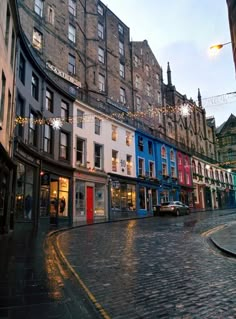 an empty street with buildings and lights on the side walk in front of each other