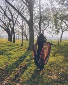 a woman is walking through the woods with her back to the camera and holding an umbrella over her head