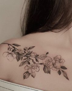 a woman's shoulder with flowers and leaves tattooed on her upper half - arm