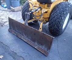 the front end of a yellow tractor with a snow plow attached to it