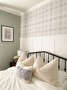 a bed with white sheets and pillows on top of it next to a wallpapered headboard