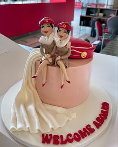 a cake with two people sitting on top of it that says welcome home in red lettering