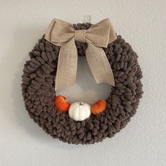 a knitted wreath with two pumpkins and a bow