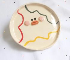 a white plate with an odd looking face on it's side and two buttons in the middle