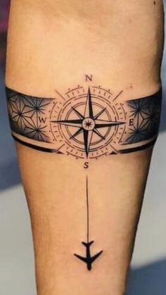 a black and white photo of a compass tattoo on the leg, with an arrow