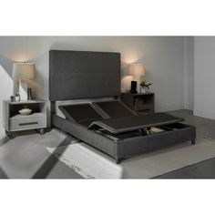 a bed with a gray headboard and foot board in a room next to two nightstands