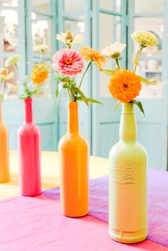 three bottles with flowers in them sitting on a table