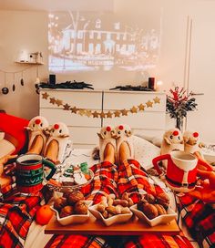 two people sitting on a couch with food in front of them and a tv screen behind them