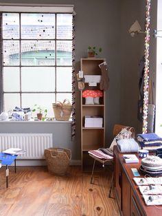 a room with wooden floors and lots of clutter on the desk, bookshelf