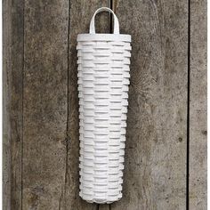 a white vase hanging on the side of a wooden wall next to a hook with a handle