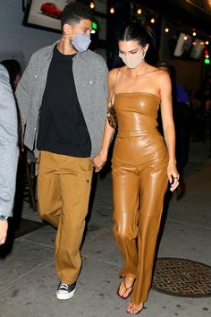 a man and woman wearing masks walking down the street