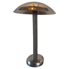 a table lamp that is on top of a metal base with a light bulb in the middle