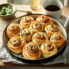 a pan filled with rolls on top of a table next to a cup of coffee