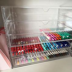 a clear plastic drawer filled with lots of different colored pens and pencils on top of a white table