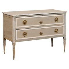 an old dresser with three drawers and gold knobs on the bottom, against a white background