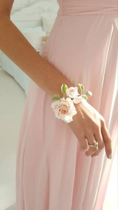 a woman in a pink dress with flowers on her wrist and hand wearing a ring