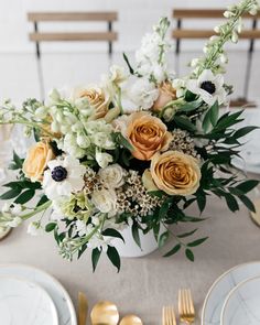 a vase filled with flowers on top of a table next to plates and silverware