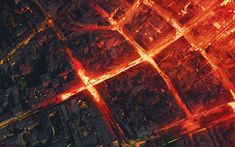 an aerial view of a city at night with red lights on the streets and buildings