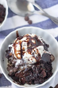 a white bowl filled with ice cream and chocolate cake dessert on top of a blue and white checkered table cloth