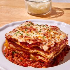 a white plate topped with lasagna covered in sauce and parmesan cheese