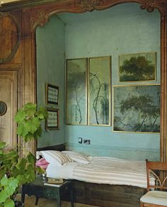 a bed sitting in a bedroom next to a green wall with pictures on the walls