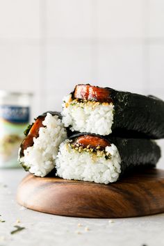 three sushi rolls stacked on top of each other with white rice and sauce in the background