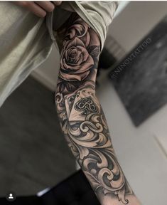 a man's arm with tattoos on it and roses in the middle of his arm