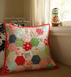 a pillow sitting on top of a window sill next to a stuffed animal and potted plant