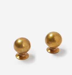 two brass knobs are shown against a white background, one has a ball on it