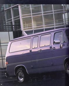 an old purple van parked in front of a tall building with glass balconies