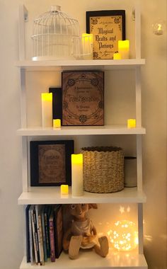 a shelf with candles, books and pictures on it