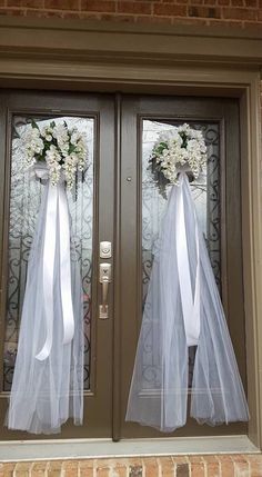 two doors decorated with white flowers and tulle bowes, one door is closed