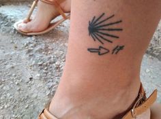 a woman's foot with an arrow tattoo on her left ankle and right leg