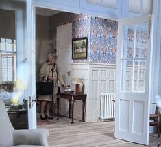 a woman is standing in the doorway of a doll house with furniture and decor on display