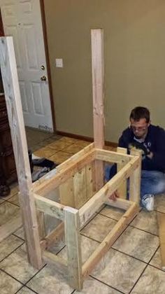 a man sitting on the floor working on some wood