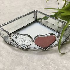 a heart shaped candle holder sitting on top of a table next to a potted plant