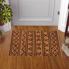 a door mat on the floor next to a potted plant in front of a white door