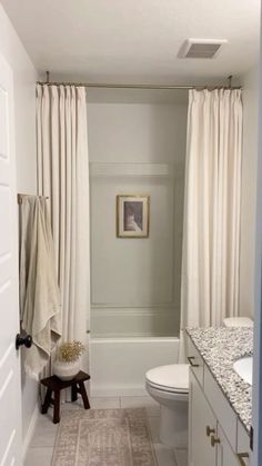 a bathroom with a white toilet sitting next to a bath tub under a shower curtain