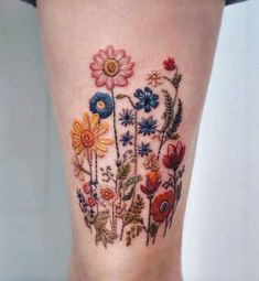 a close up of a person's leg with colorful flowers on the bottom of it