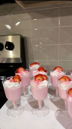 there are many glasses with strawberries in them on the kitchen counter, ready to be served