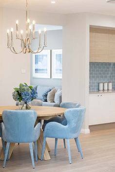 a dining room table with blue chairs and a chandelier hanging from the ceiling