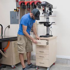 a man working on a drill press in a shop with workbench and tools